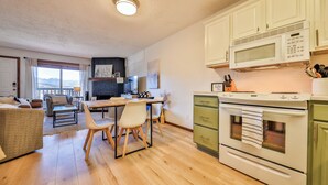Una cucina moderna con mobili bianchi, un forno a microonde e un piano cottura. C'è una zona pranzo con tavolo e sedie.