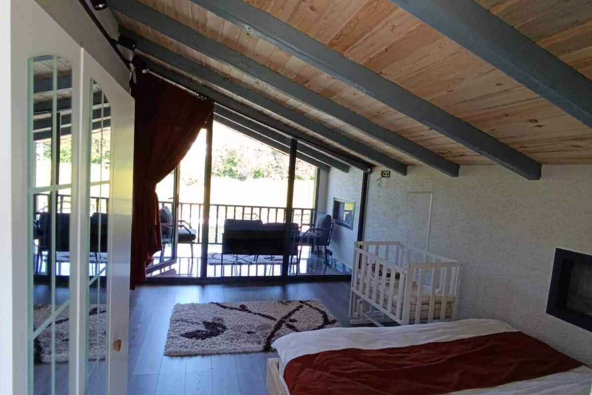 Ein Schlafzimmer mit Bett, Fenster, Tür und Blick nach außen.