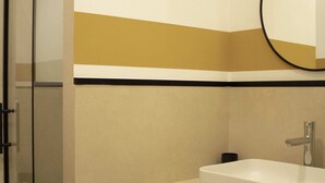 Ein Badezimmer mit Duschkabine aus Glas, einem weißen Waschbecken, einem Spiegel und einem Handtuchhalter.