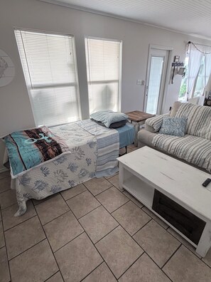 Una habitación con una cama, un sofá, una mesa de centro y una puerta.
