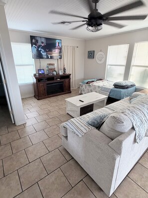 A living room with a sofa, TV, and ceiling fan.
