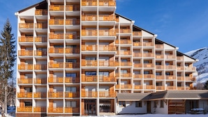 A multi-story hotel with balconies, a ski slope in the background, and a mountain view. - Snowfront Stay for Four Guests (Les Deux Alpes)