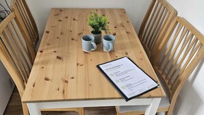 A wooden table with two grey mugs, a small potted plant, and a welcome guide. - Central Bristol Apartment with Parking | Sleeps 6 (Bristol City)
