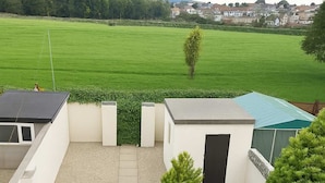 Terraço no telhado com vista para um campo verde e casas ao longe.