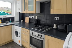 A modern kitchen with a washing machine, a stove, and a toaster.