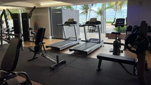 Ett gym med löpband, styrketräningsmaskiner och en bänk.