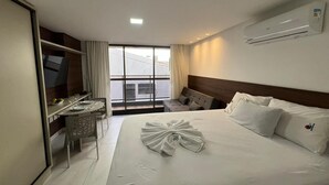Ett hotellrum med en säng, ett skrivbord, en tv och utsikt över omgivningarna.