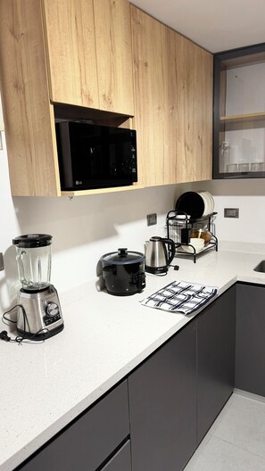 A kitchen with wooden cabinets, a microwave, a coffee maker, a blender, and a kettle. - Modern apartment in the heart of Huamanga, Ayacucho. (Ayacucho)