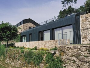 Ein modernes Gebäude mit einer Steinfassade, großen Fenstern und einem Metallbalkon.