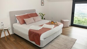 Een moderne slaapkamer met een bed, nachtkastje en uitzicht door een groot raam.