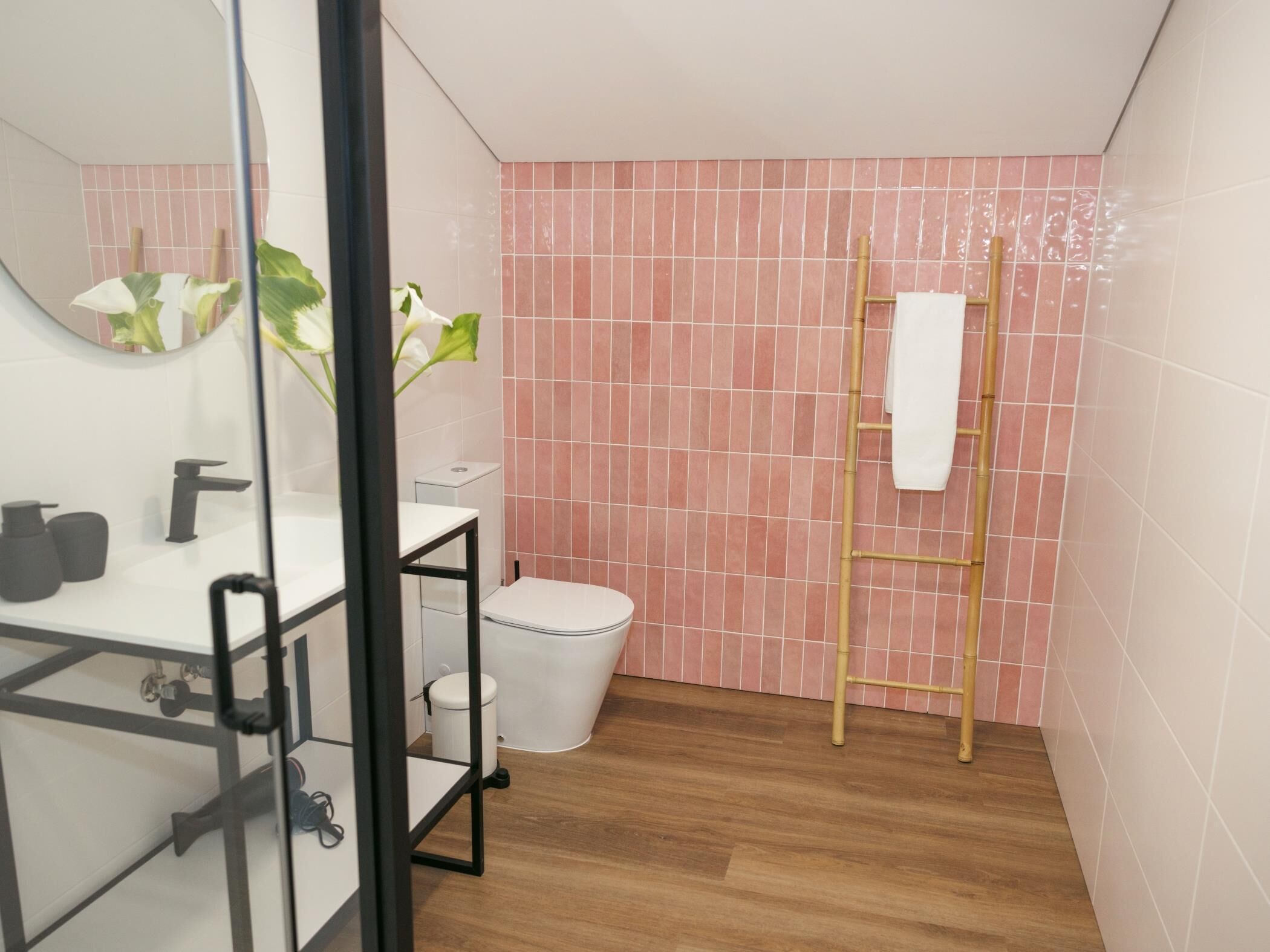 A bathroom with a toilet, sink, mirror, and a towel rack.