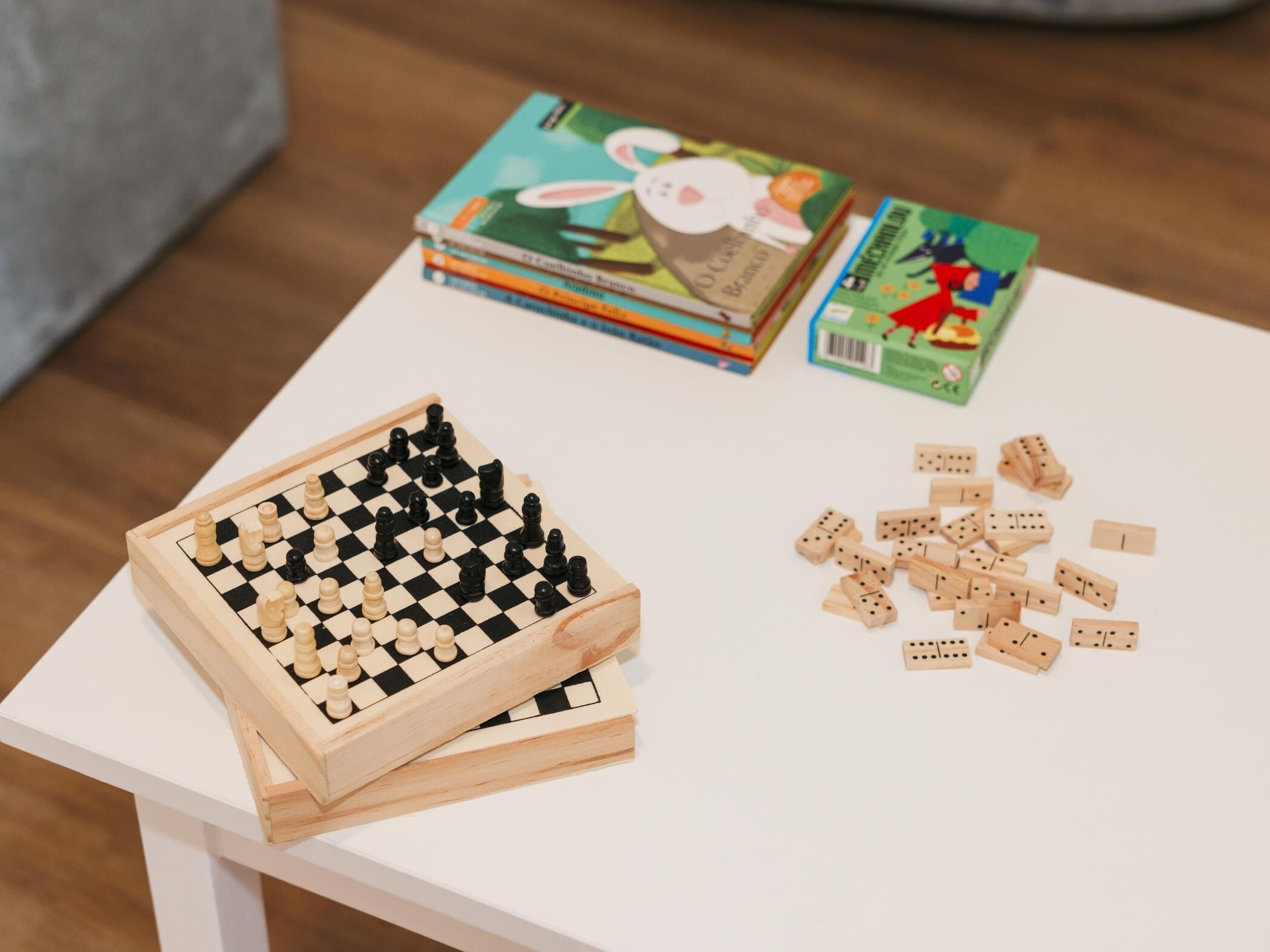 A chessboard, dominoes, and books on a white table.