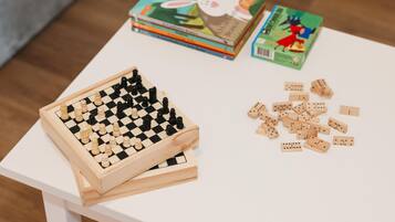 A chessboard, dominoes, and books on a white table.