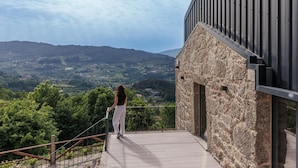 Ein Balkon mit Steinmauer und Metallgeländer mit Blick auf ein Tal.