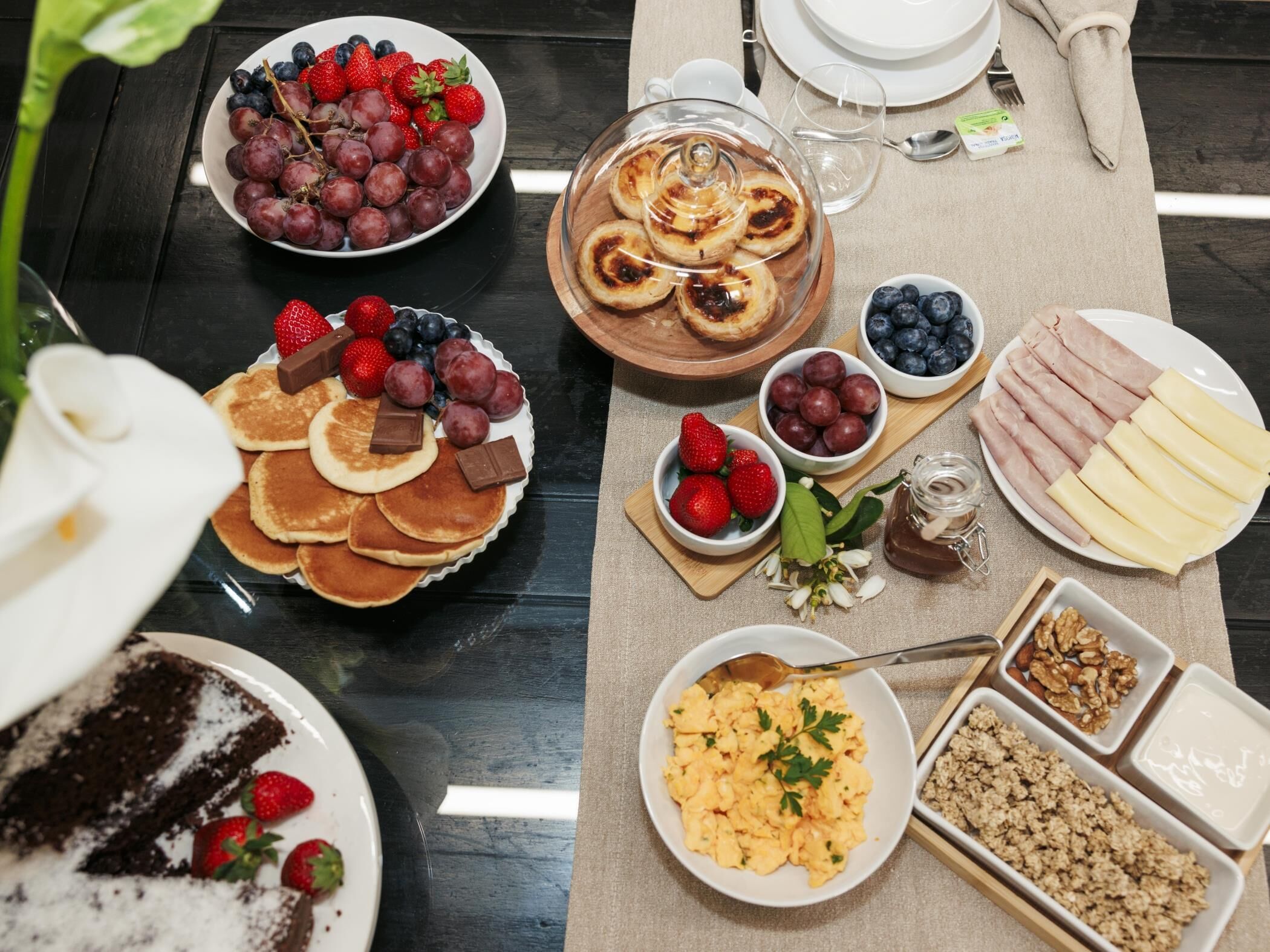A breakfast buffet with various food items including pancakes, pastries, fruits, and dairy products.