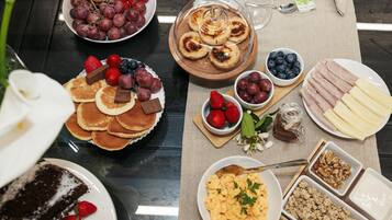 A breakfast buffet with various food items including pancakes, pastries, fruits, and dairy products.