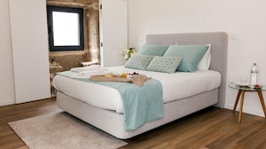 Ein Schlafzimmer mit Bett, Nachttisch und Blick auf eine Steinmauer.