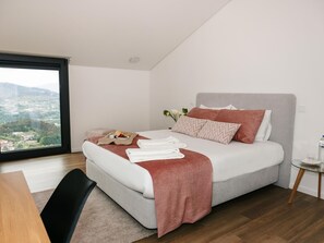 Une chambre à coucher moderne avec un lit, une petite table et une vue sur un paysage.