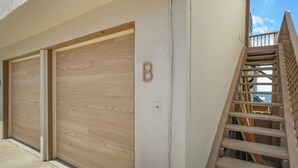Ein Gebäude mit einer Holztür zur Garage, einem Buchstaben 'B' an der Wand und einer Holztreppe.