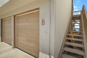 Ein Gebäude mit einer Holztür zur Garage, einem Buchstaben 'B' an der Wand und einer Holztreppe.