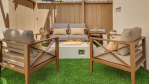 Eine Terrasse mit Feuerschale, zwei Sofas und zwei Sesseln.