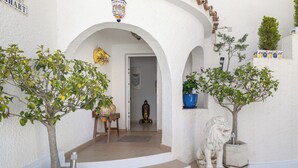 A white-walled building with a staircase leading to an interior doorway, a statue of a lion, and potted plants. - Villa Las Chicas the authentic Andalusian retreat (Fuengirola)