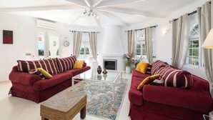 A spacious living room with two red sofas, a glass coffee table, and a fireplace. - Villa Las Chicas the authentic Andalusian retreat (Fuengirola)