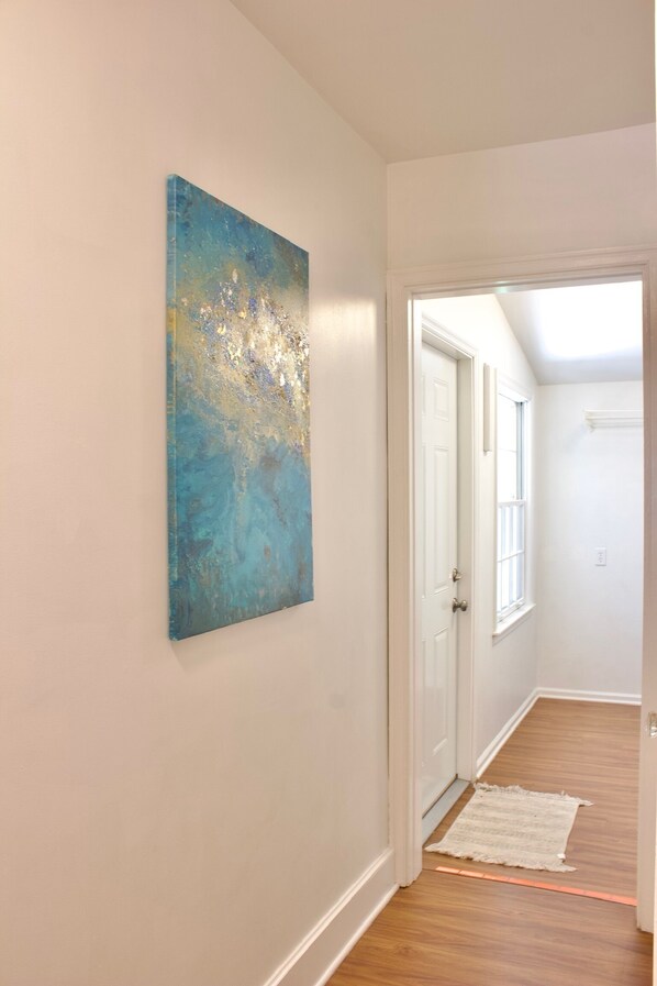 A hallway with a door, a light switch, and a white rug on the floor.
