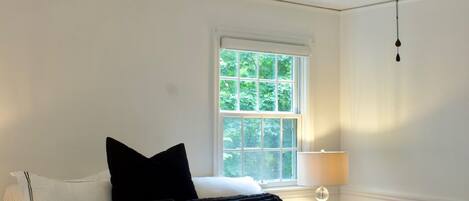 A bedroom with a bed, a window, a ceiling fan, and a nightstand.