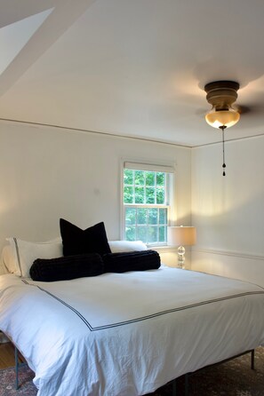 Ein Schlafzimmer mit Bett, Fenster, Deckenventilator und Nachttisch.