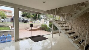 Amplio espacio interior con una escalera, un vidrio que da al exterior y piso de baldosas.