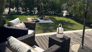 Eine Terrasse im Freien mit Korbmöbeln, einem weißen Sonnenschirm und einem kleinen Tisch.