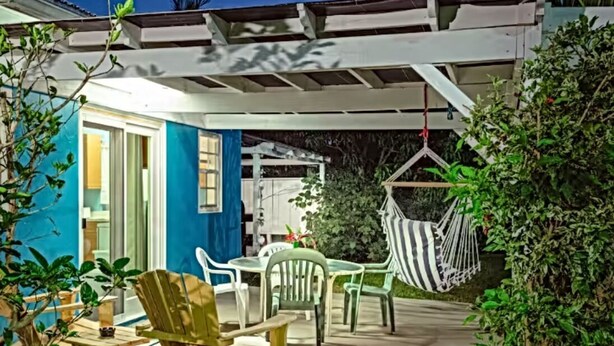Eine Terrasse mit Tisch und Stühlen, einem Hängesessel und einem überdachten Bereich mit Decke.