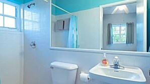 Ein Badezimmer mit Toilette, Waschbecken mit Seifenspender und großem Spiegel.