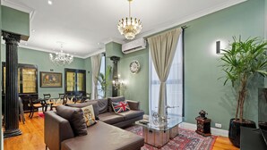 Ein Wohnzimmer mit einer Couch, einem Glastisch, einer Kandelaber und einem großen Fenster mit Vorhängen.