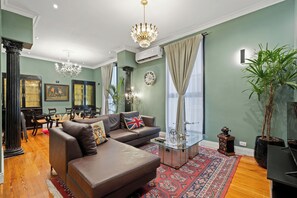 A living room with a sofa, a glass coffee table, a chandelier, and a large window with curtains. - Bold Designer Apartment near Puerto Madero (Buenos Aires)