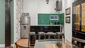 Eine Küche mit grünen Fliesen an der Spritzschutzwand, einem Edelstahlkühlschrank und einer Bar mit Hockern.