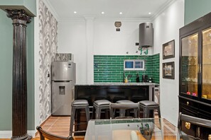 A kitchen with a green-tiled backsplash, a stainless steel refrigerator, and a bar area with stools. - Bold Designer Apartment near Puerto Madero (Buenos Aires)