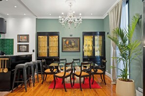 A dining area with a glass table, wooden chairs, a chandelier, and a large potted plant. - Bold Designer Apartment near Puerto Madero (Buenos Aires)