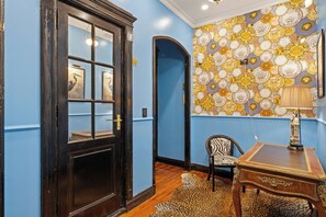 A room with a blue wall, a wooden door with glass panels, a patterned wallpaper, a zebra-striped chair, and a small table with a lamp. - Bold Designer Apartment near Puerto Madero (Buenos Aires)