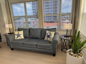 A grey sofa with star and crab pillow designs, positioned in front of a window with blinds, flanked by two small tables with lamps, and a potted plant on the right. - Premium Oversized Vacation Condo! Steps to the Broadwalk & Beach.
Game Lounge. (Hollywood)