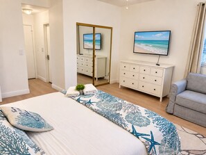 Une chambre à coucher avec un lit, une commode, un téléviseur et une chaise.