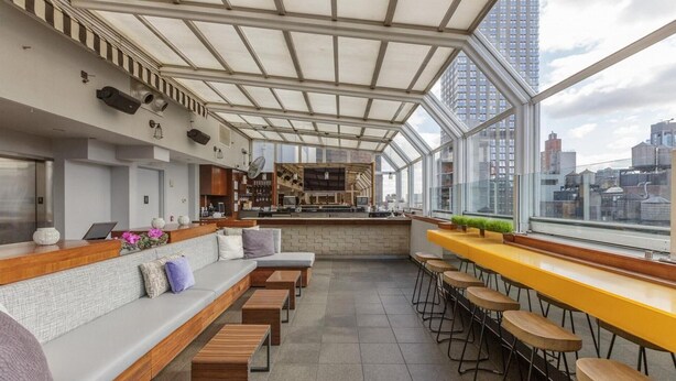 A modern bar area with seating and a kitchen in the background.