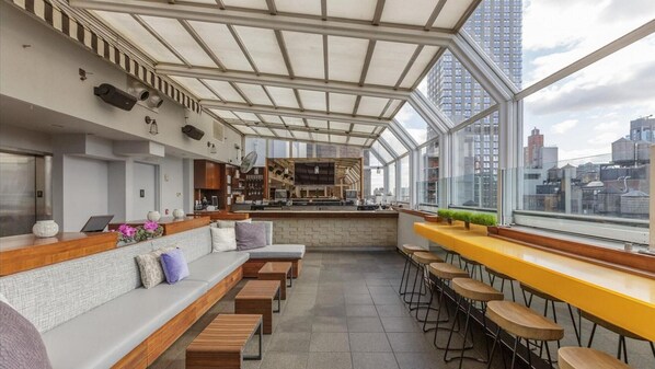 A modern bar area with seating and a kitchen in the background.