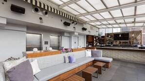 Un área de bar moderna con una barra larga, asientos acolchados y un techo alto con tragaluces.