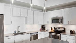 A modern kitchen with white cabinets, stainless steel appliances, a dishwasher, and a coffee maker. - Stylish Austin Escape Near Music, Dining & Spacious 1BR Resort Stay (Austin)