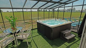 A glass-enclosed outdoor area with a hot tub, seating, and a potted plant. - Evasion Campagne : Spa, Sauna, Sport (ST MARDS DE BLACARVILLE)
