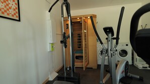 A home gym with exercise equipment, a washing machine, and a wooden door leading to a laundry room. - Evasion Campagne : Spa, Sauna, Sport (ST MARDS DE BLACARVILLE)