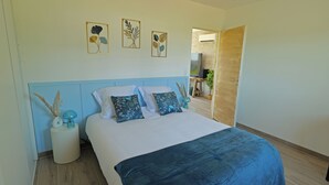 A bedroom with a bed, pillows, a bedside table, a vase, and wall art. - Evasion Campagne : Spa, Sauna, Sport (ST MARDS DE BLACARVILLE)