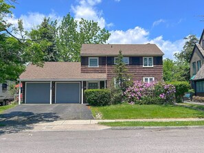 A two-story house with a garage, a driveway, and a well-maintained lawn with flowering bushes. - 3500sf, Arcade, 6bdrm,  2 kitchen, 3baths, Parking (Niagara Falls)